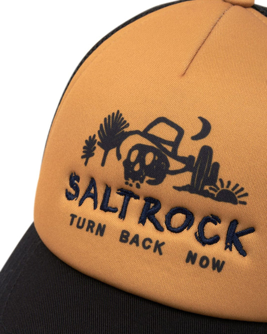 A close-up of an orange and black Saltrock Last Stop Trucker Cap with embroidered branding and "turn back now" graphics.