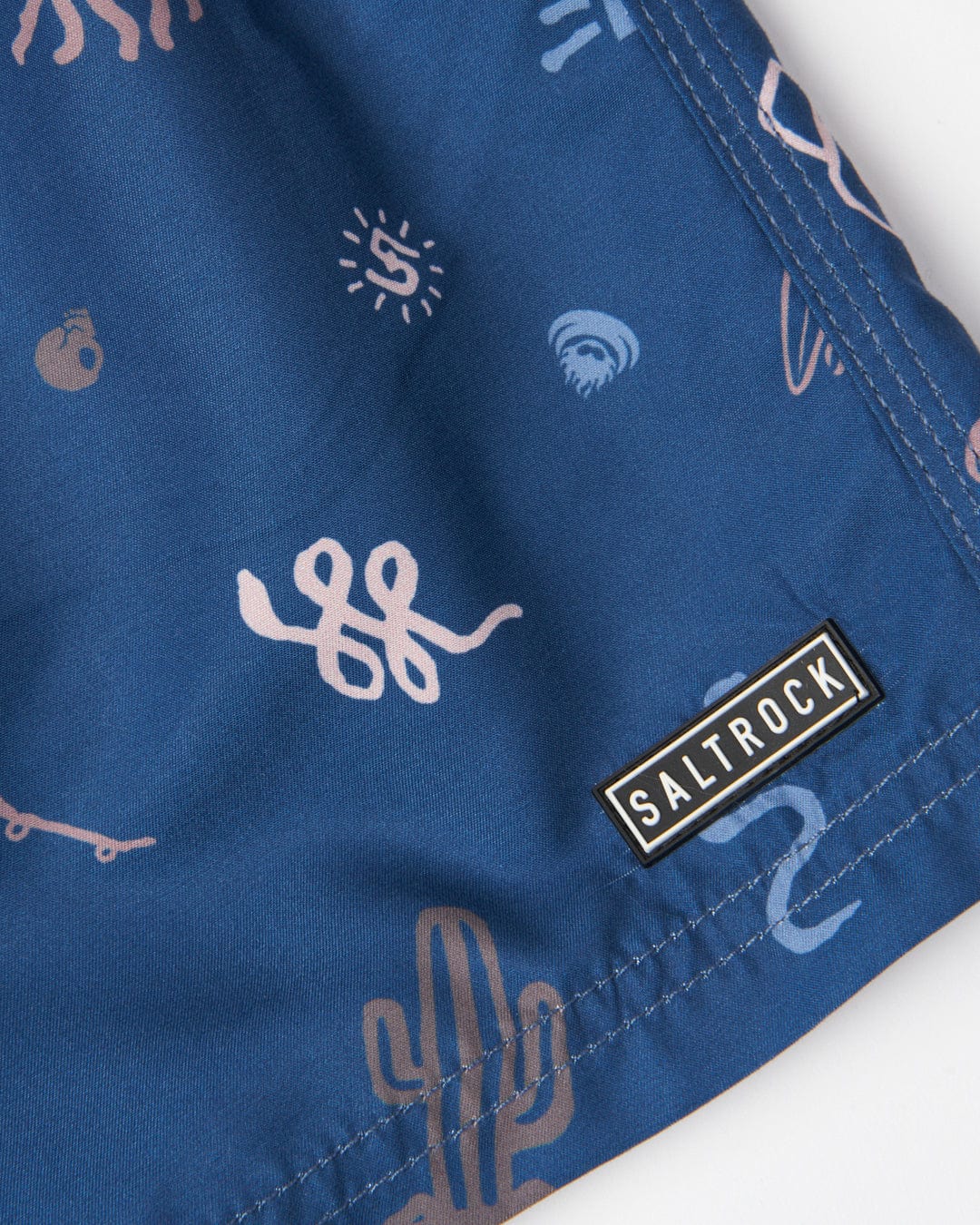 Close-up of a blue fabric with white abstract all over print and the Saltrock logo on a black label.