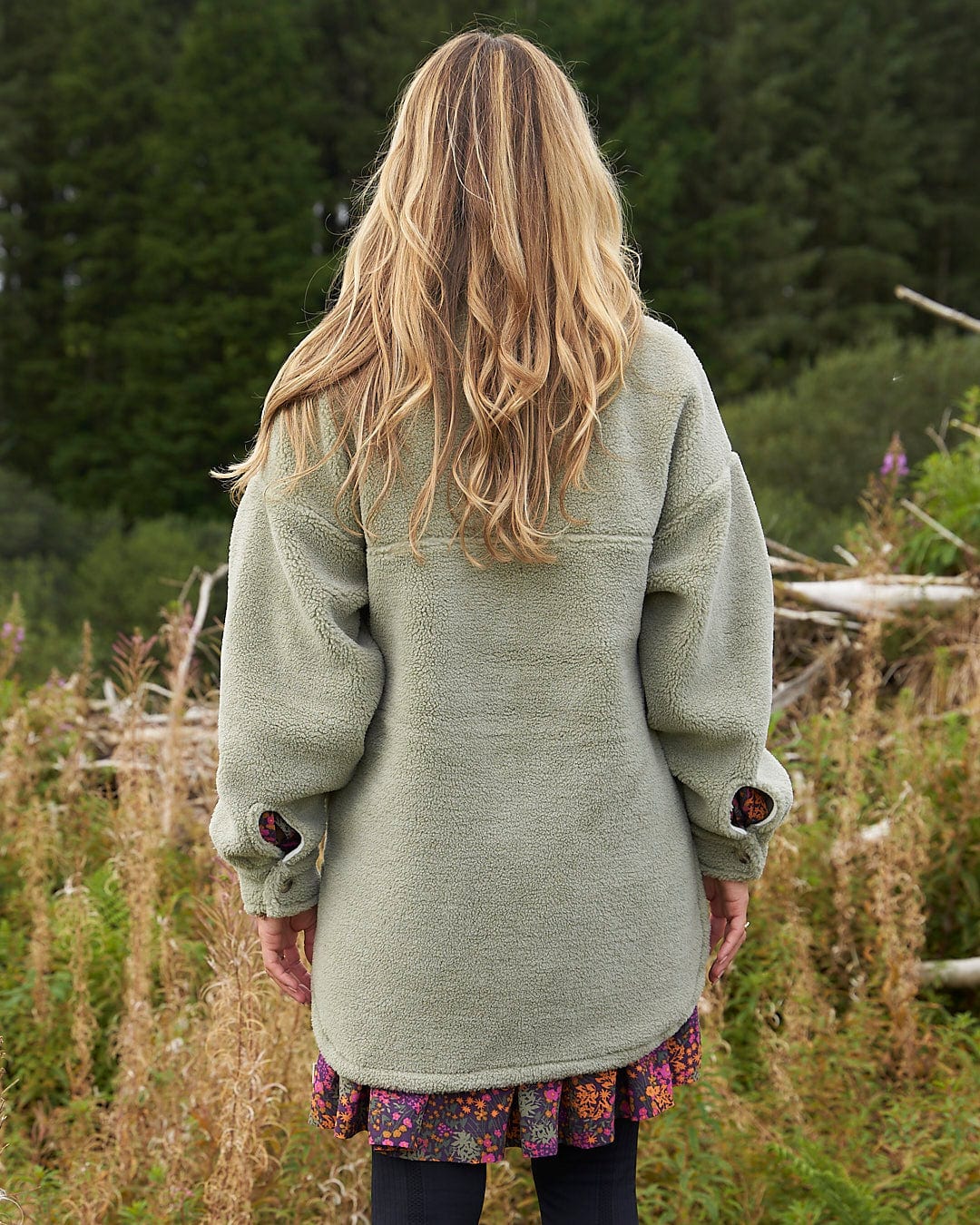 A woman standing in a field wearing the Laurie - Womens Sherpa Fleece Coat - Green by Saltrock.