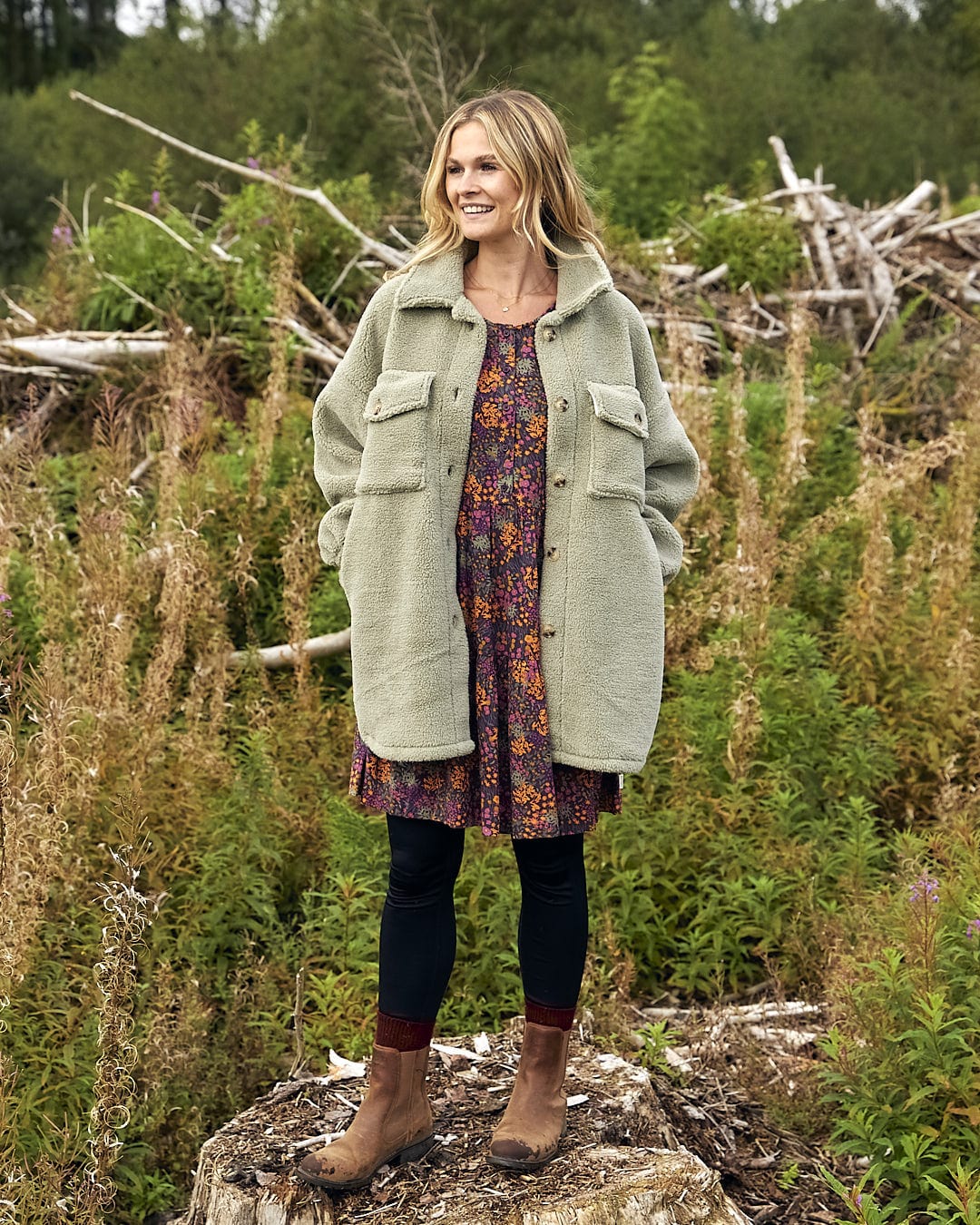 A woman standing on top of a rock in a field wearing the Laurie - Womens Sherpa Fleece Coat - Green by Saltrock.