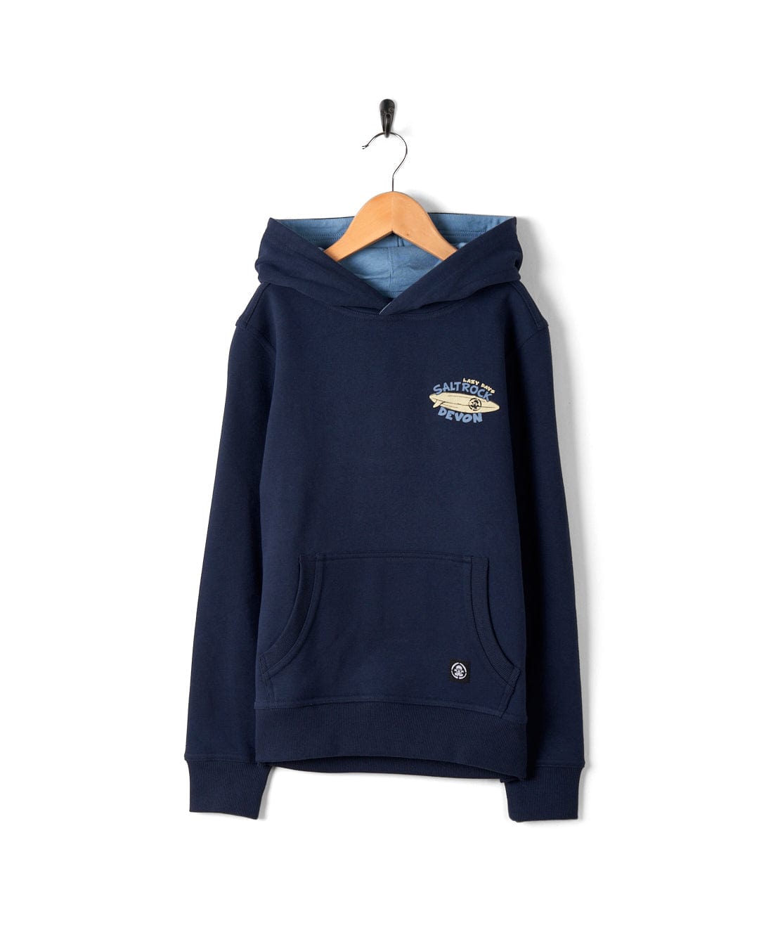 A navy blue Saltrock branded Lazy Location Wales - Recycled Kids Hoodie - Blue with a front pocket and logo embroidery, hanging on a wooden hanger against a white background.