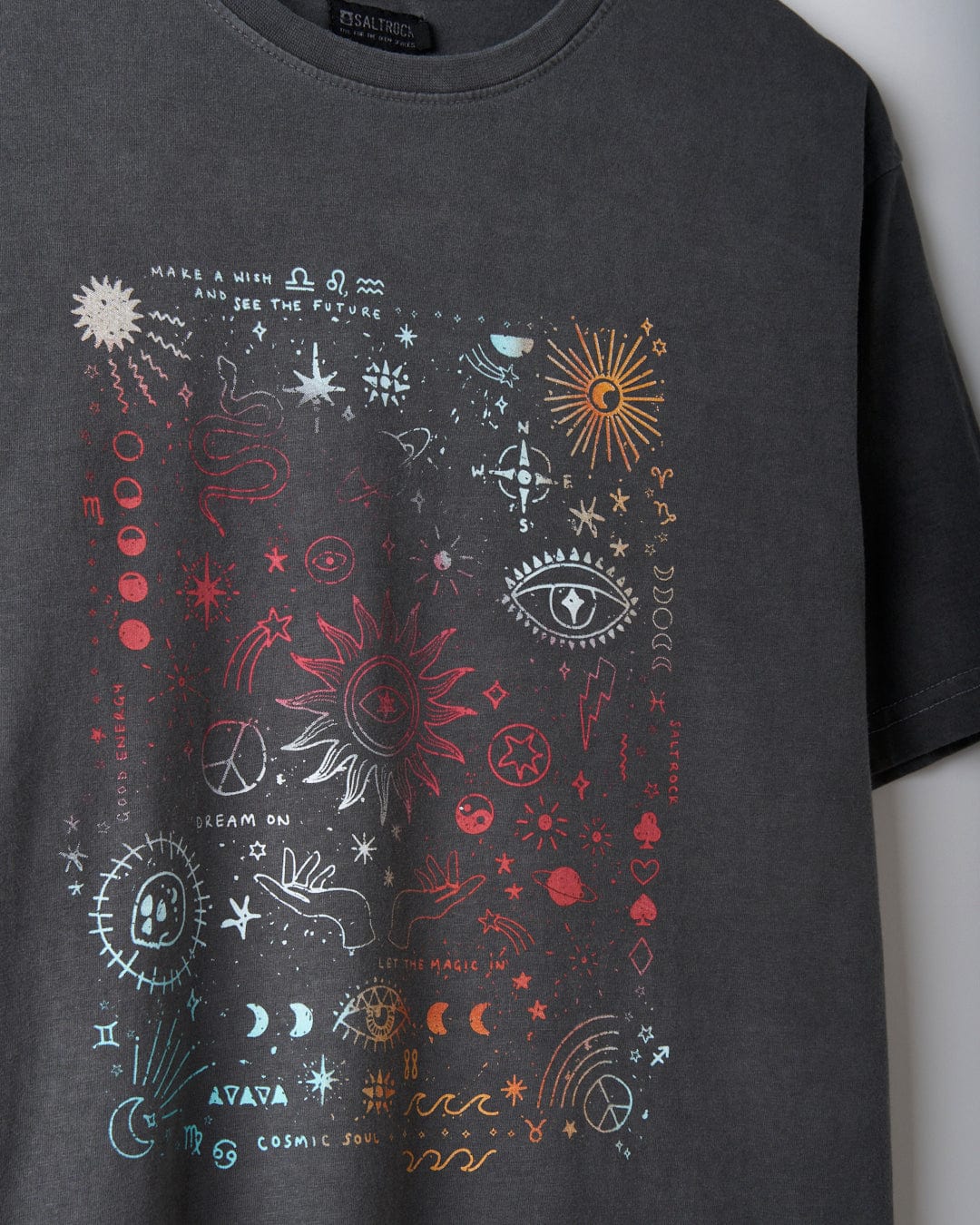 The "Let The Magic In - Women's Oversized T-Shirt" by Saltrock, in a washed grey color, is crafted from 100% cotton and showcases an intricate design adorned with various cosmic and mystical symbols such as stars, planets, eyes, and zodiac signs printed in a vibrant mystical gradient.
