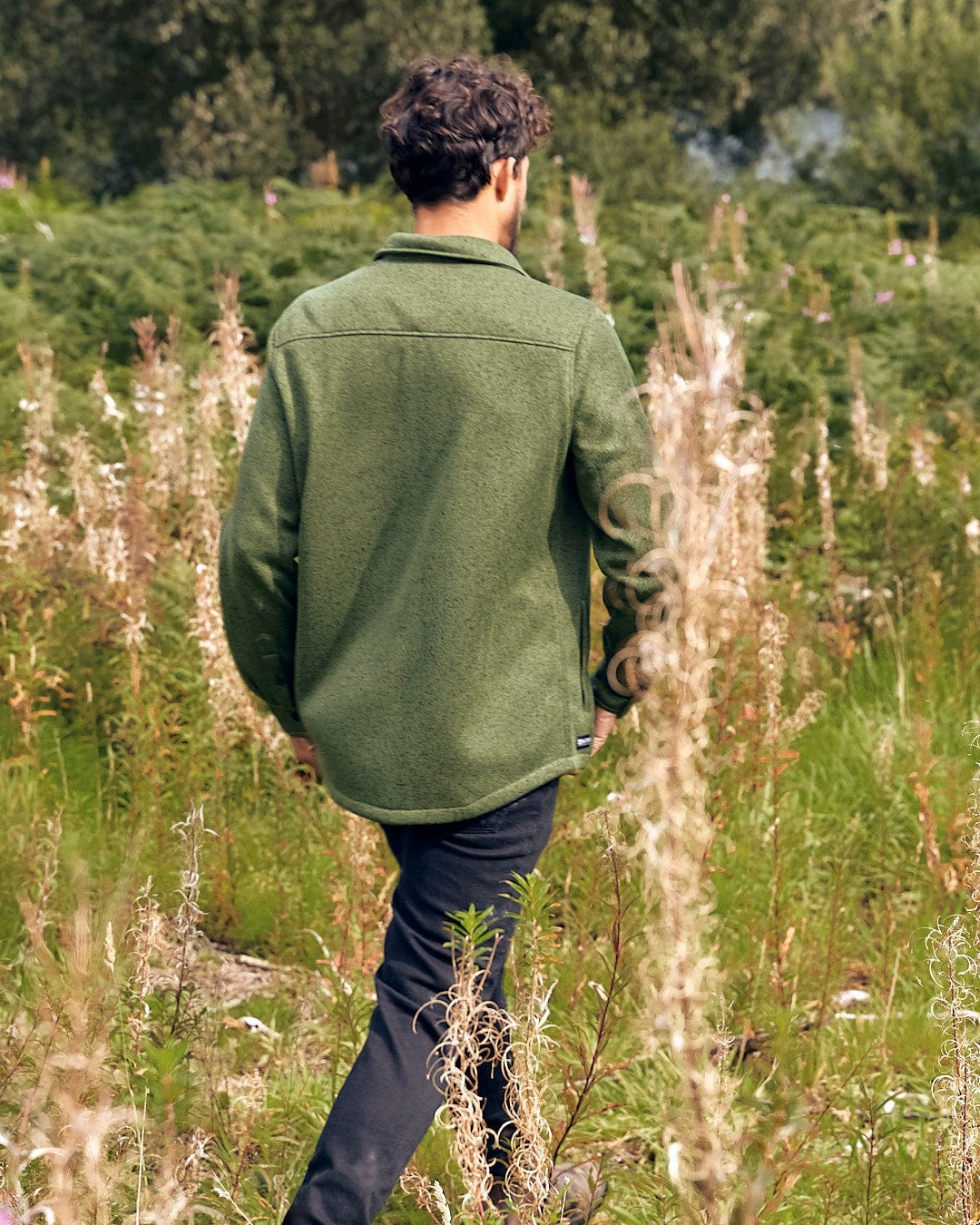 A man walking through a field of tall grass wearing a Saltrock Levick Dark Green Mens Long Sleeve Shirt.
