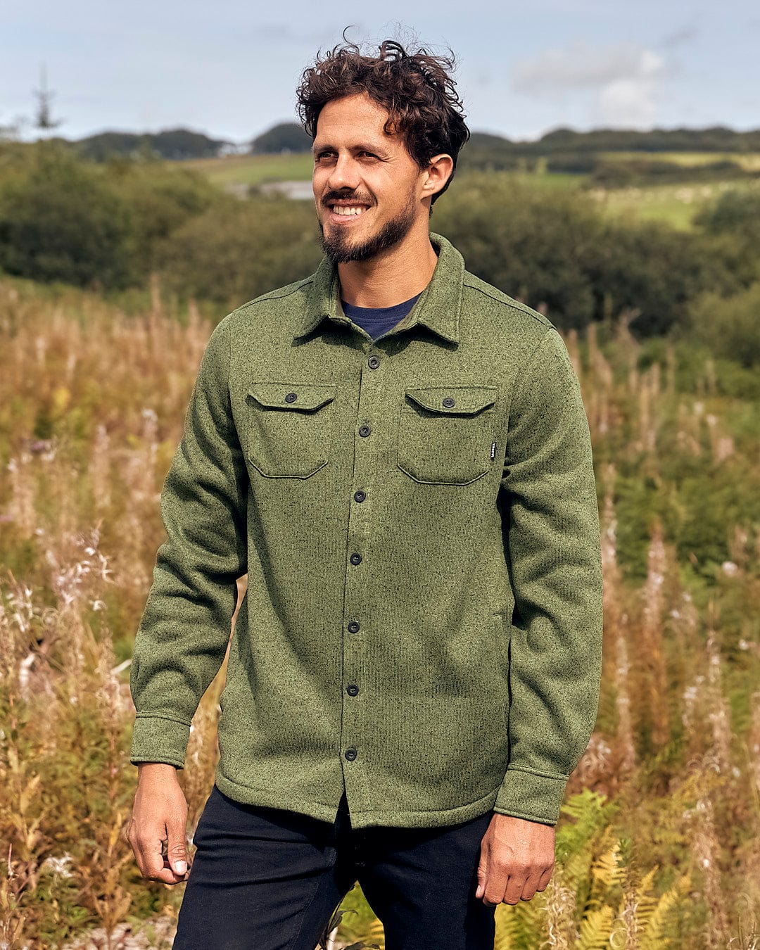 A man in a stylish green Saltrock Levick Mens Long Sleeve Shirt standing in a field with Saltrock branding.