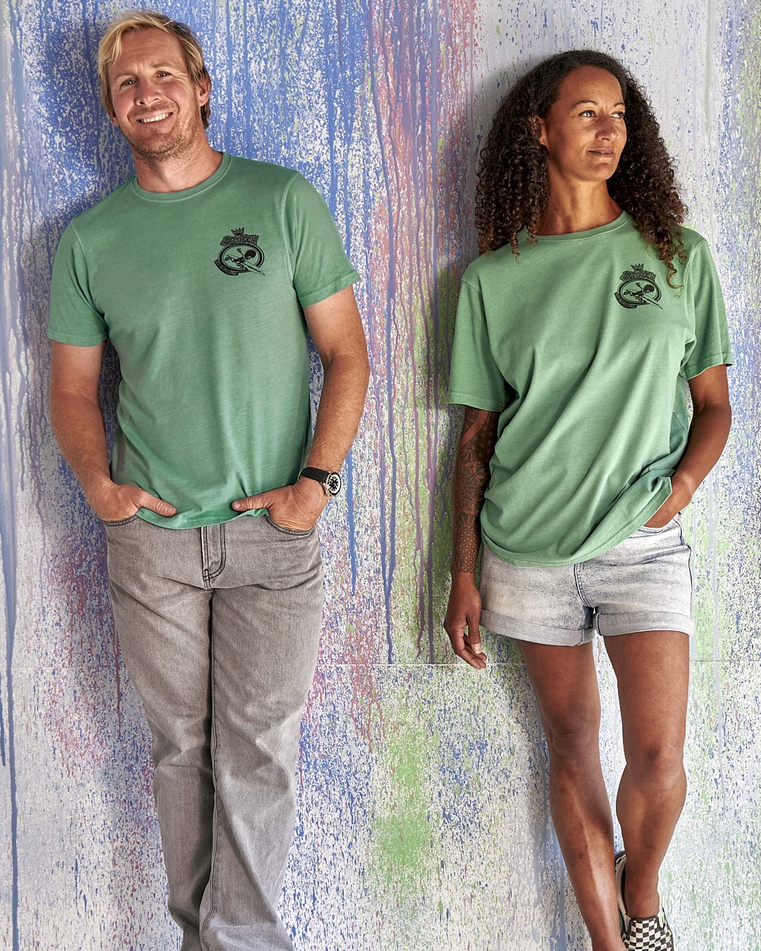 A man and woman standing next to each other wearing Saltrock's Little Creatures - Limited Edition 35 Years T-Shirts in green.
