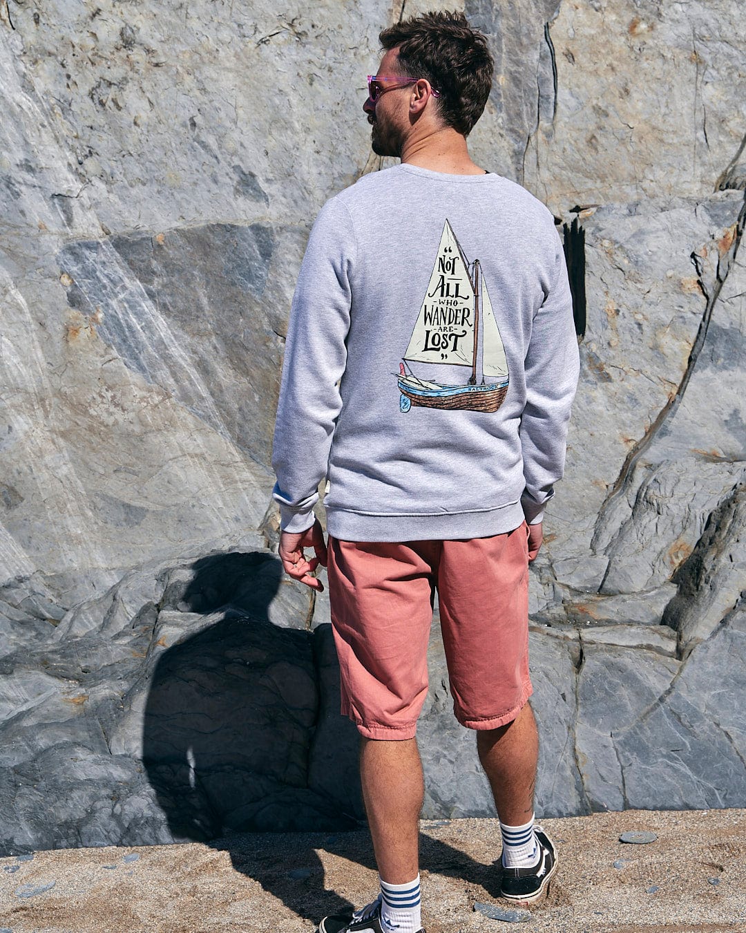 A man standing on a rock with a Lost Ships - Mens Crew Sweat - Grey sweatshirt from Saltrock.
