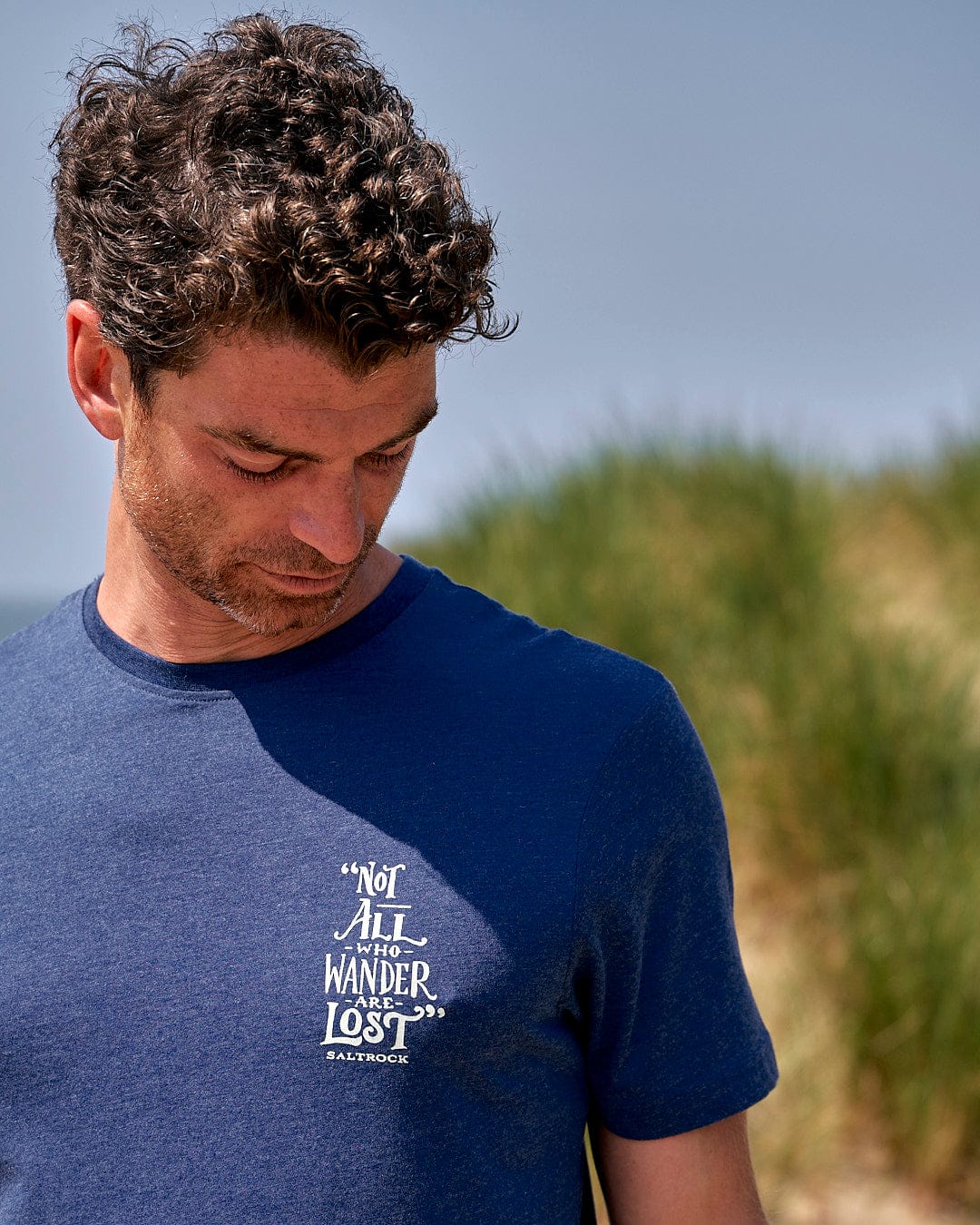 A man wearing a Lost Ships - Mens Short Sleeve T-Shirt - Blue with a quote on it.