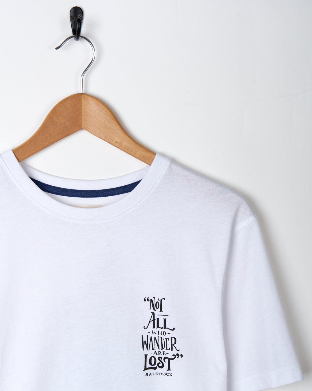 A white Saltrock Lost Ships Short Sleeve T-shirt with a text quote "not all who wander are lost" hanging on a wooden hanger against a white background.