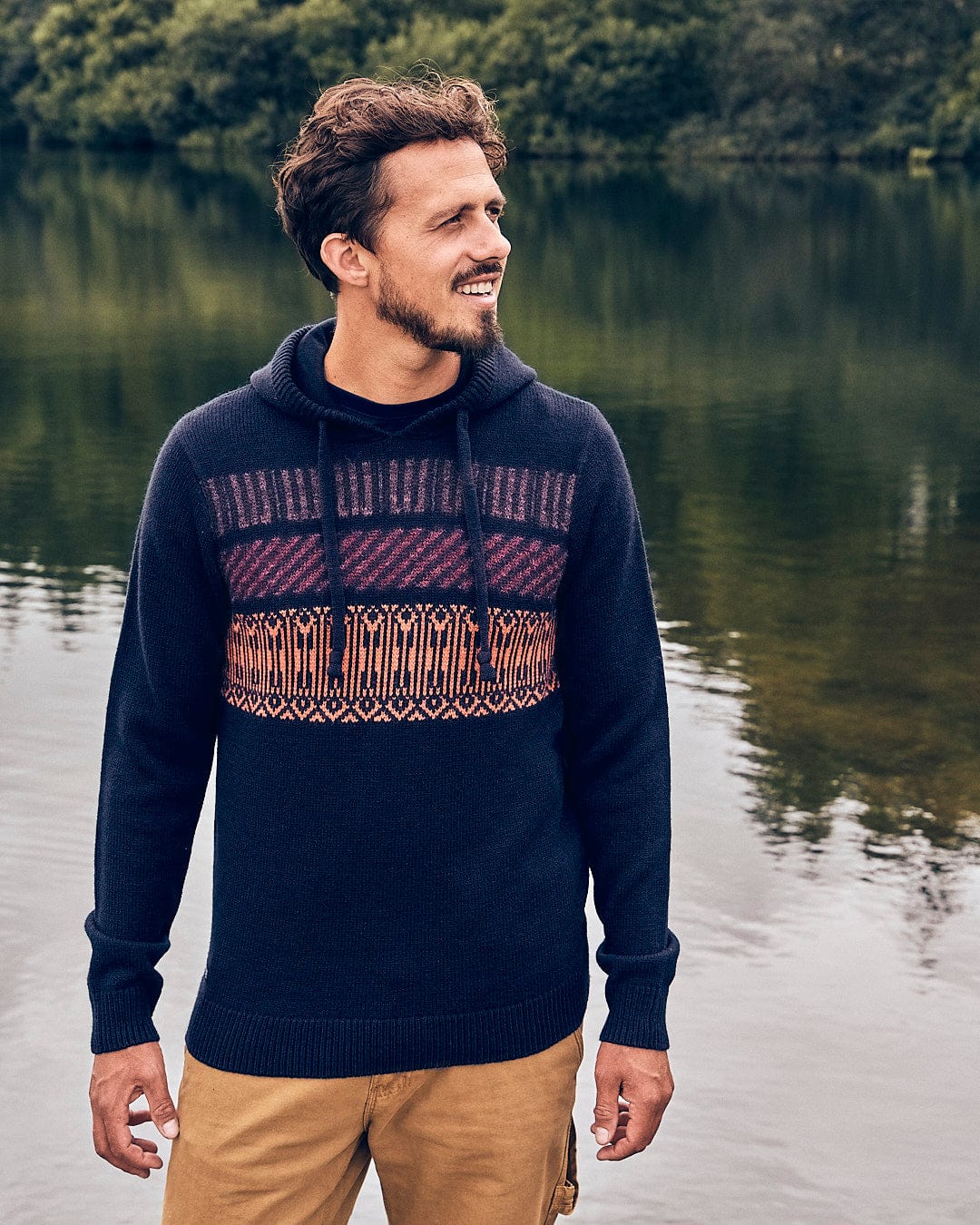 A man standing next to a lake wearing a Saltrock - Lukas Mens Knitted Hoodie.