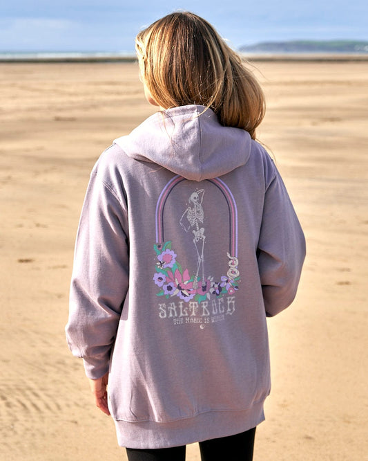 A woman wearing a Magic Within - Womens Zip Hoodie - Lilac by Saltrock with thumb holes on the beach.