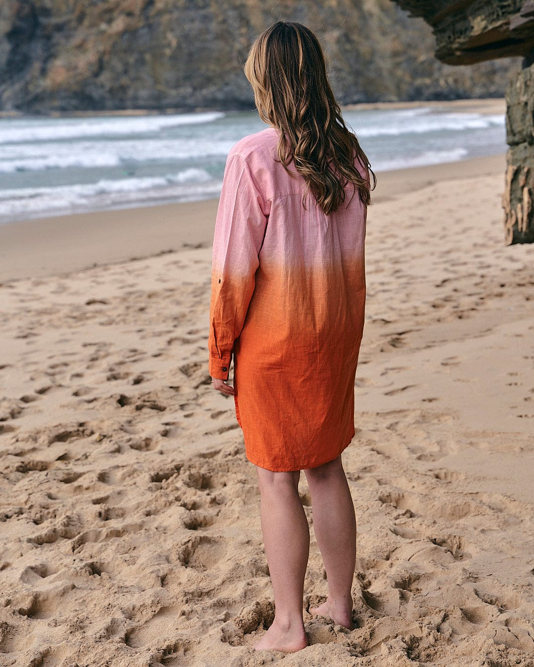 A woman standing on the beach in a Saltrock Manina - Womens Dip Die Beach Shirt - Orange dress.