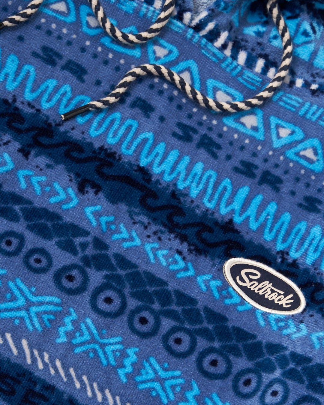 Close-up of a blue vintage stripe patterned fabric with a "Saltrock" logo tag and a white twisted rope detail.