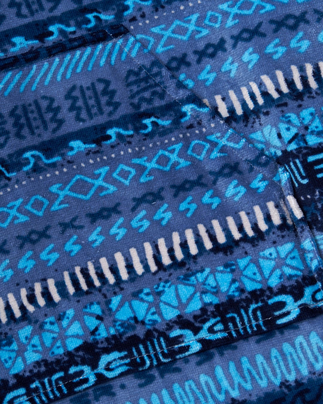 Close-up of a Saltrock Marks - Changing Towel - Blue with a black vintage stripe patterned fabric with tribal-inspired designs.