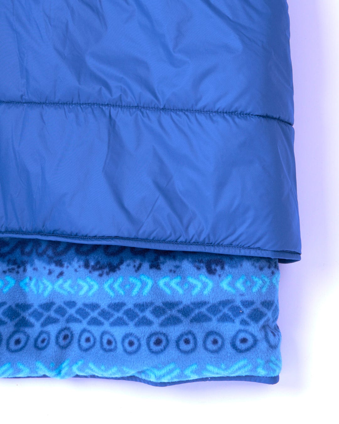 A water-resistant Saltrock Marks - Unisex Recycled Reversible Poncho - Blue blanket made from recycled material on a white surface.