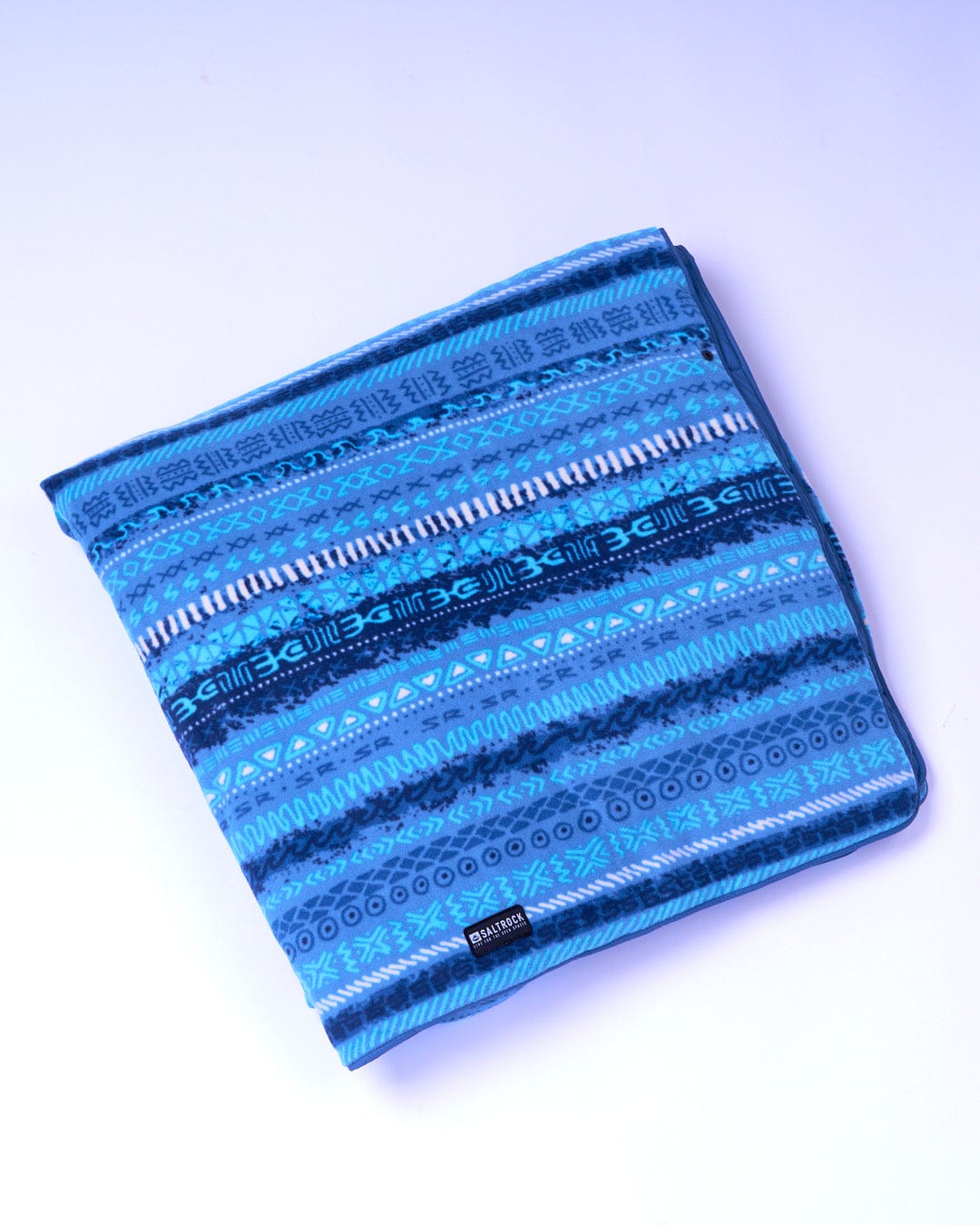 A Saltrock blue striped blanket on a white surface made from recycled material.