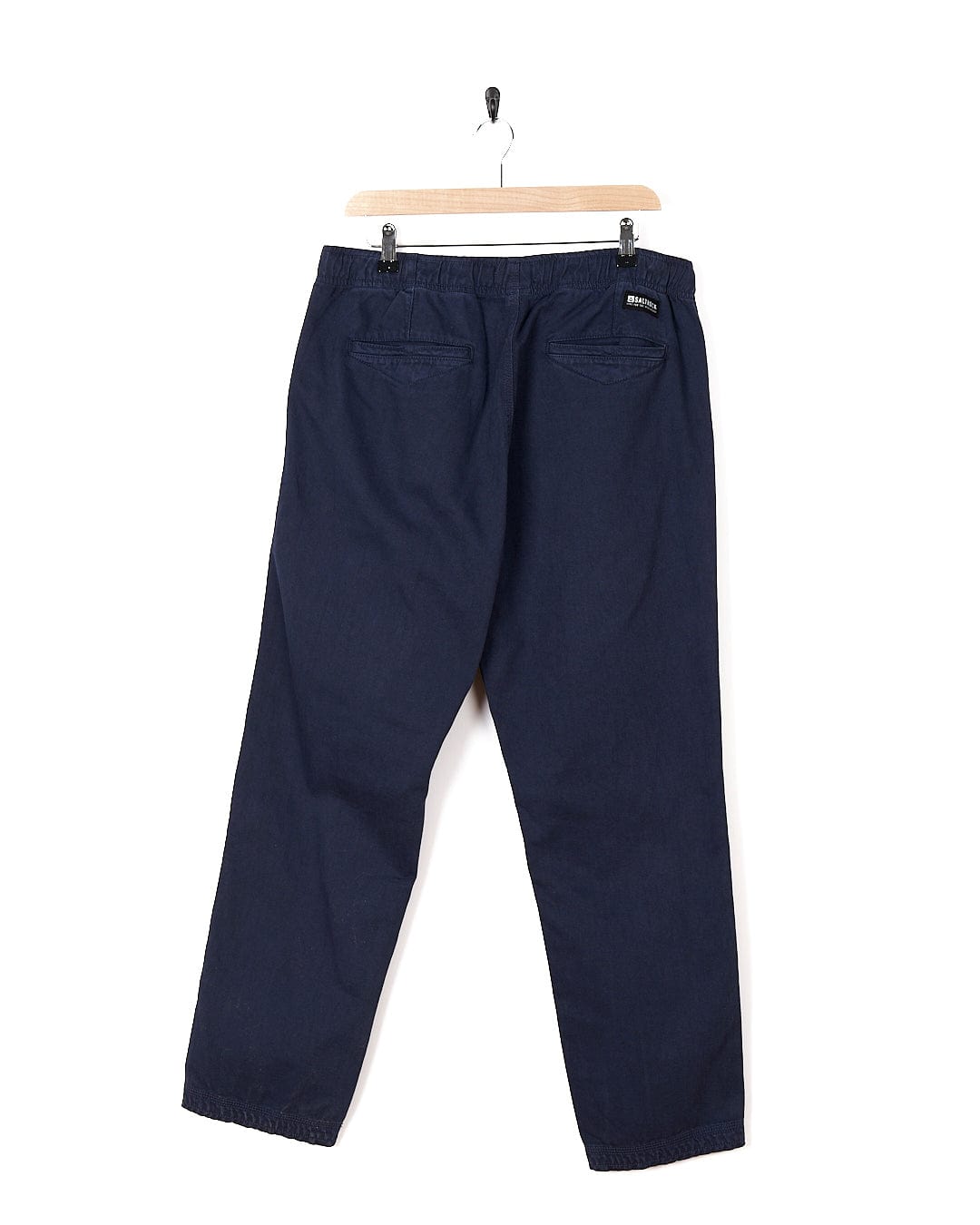 A pair of Saltrock Meddon Mens Twill Trouser in navy color hanging on a hanger.