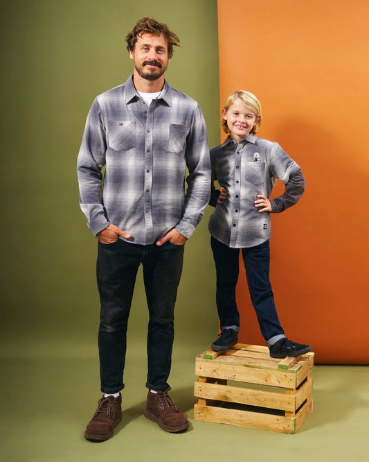 A man and a child standing next to a wooden crate featuring Saltrock branding, showcasing the Slacker - Kids Shirt - Grey.