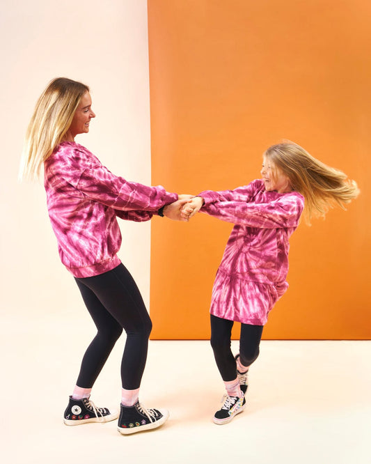 A stylish mother and daughter dancing in a cool Saltrock Effie - Kids Tie Dye Sweatdress - Pink hoodie.