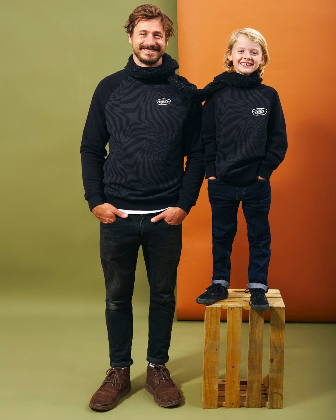 A man and a boy posing for a photo in a black sweatshirt featuring Saltrock branding. The sweatshirt is the Grip It - Kids Crew Neck Sweat - Black by Saltrock.