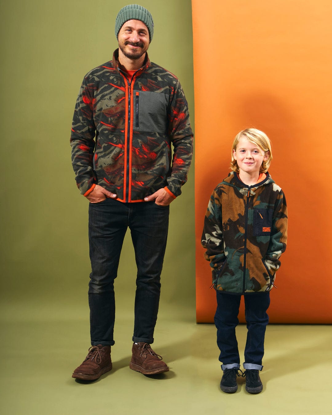 A man and a boy standing next to each other in front of Saltrock's Communicado - Kids Camo Zip Fleece - Dark Green jackets, ready for outdoor adventures.