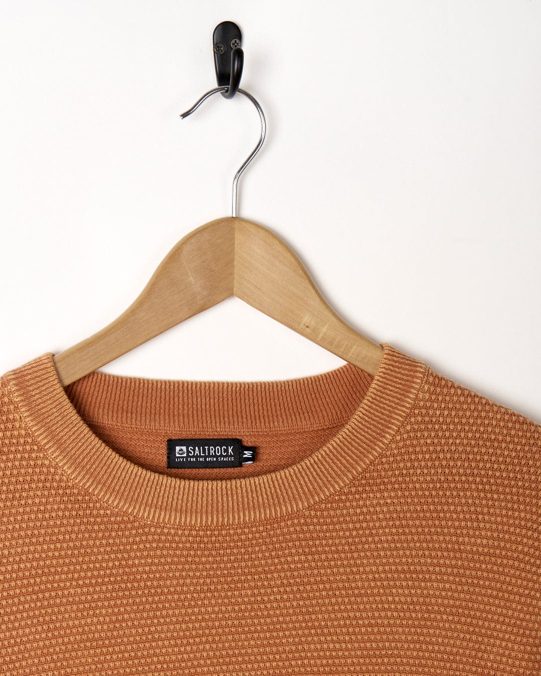 A Moss - Mens Washed Knitted Crew - Orange sweater hanging on a hanger.