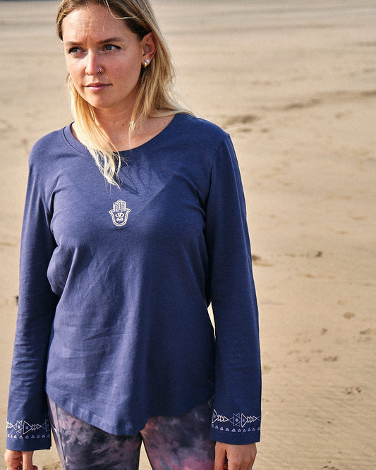 A woman wearing a Saltrock Mountain Rise - Womens Flared Sleeve T-Shirt - Purple standing on the beach.