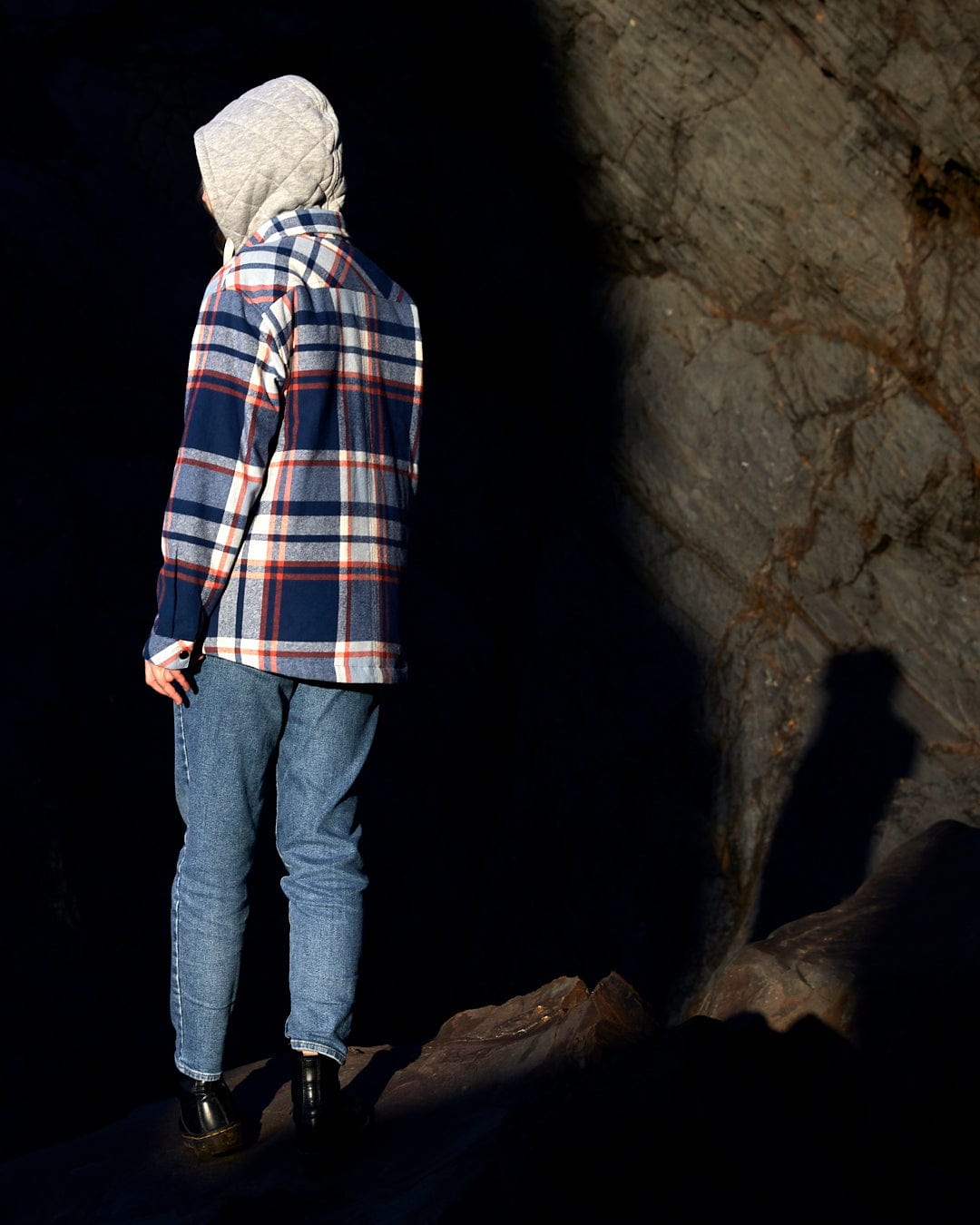 A person standing on a rock wearing a Saltrock Myla Womens Hooded Checked Shacket - Blue Check with zip fastening and front pockets.