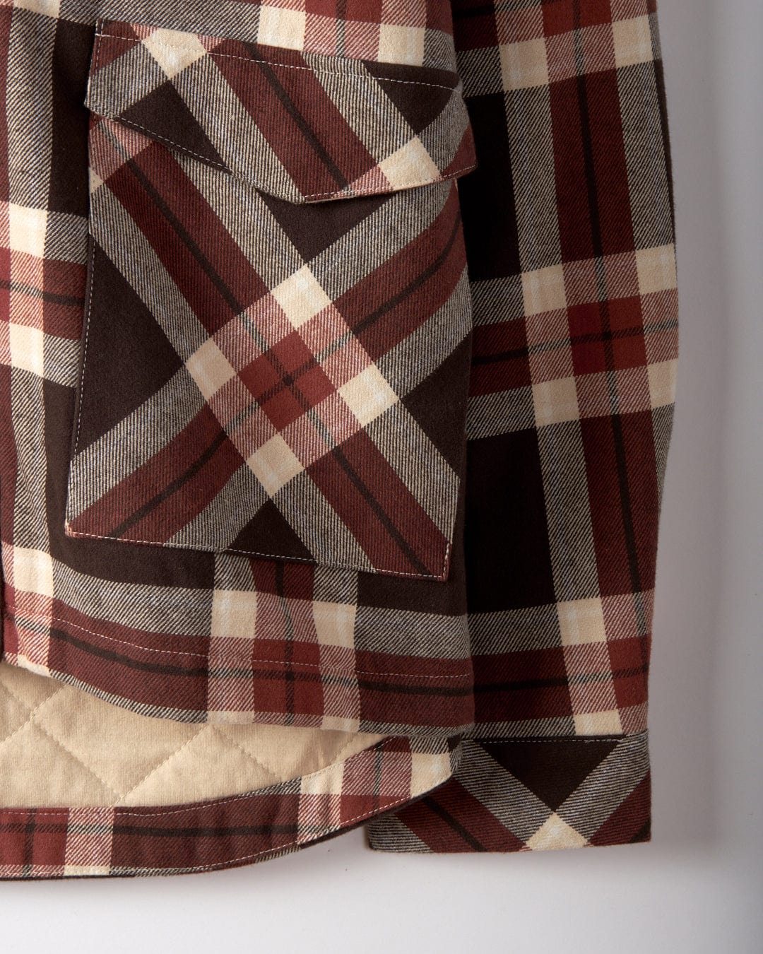 Close-up of the Saltrock Myla Women's Hooded Shacket in brown check plaid with a front pocket, visible stitching, and an oversized fit, shown against a plain background.