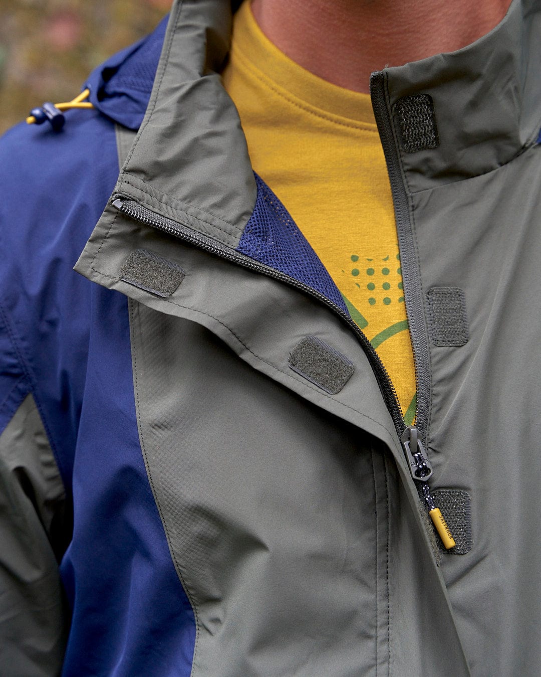 A close up of a man in a Saltrock Nevis - Mens Waterproof Mac - Blue/Green jacket.