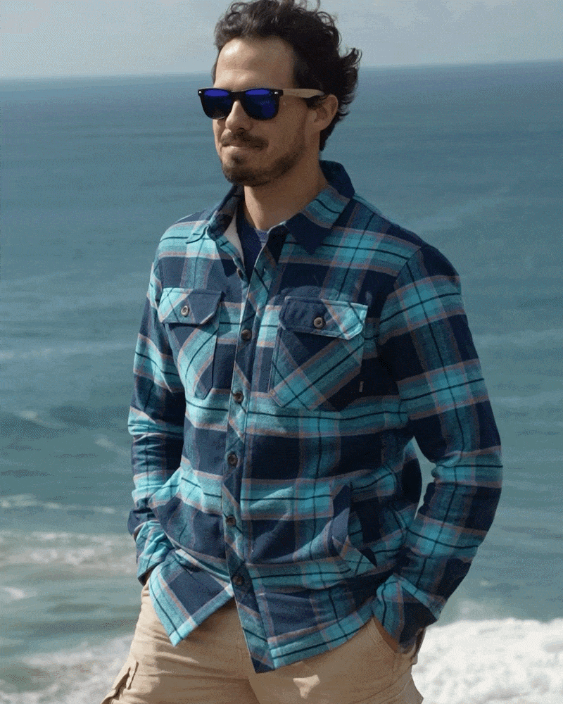 A man wearing a Saltrock Ocean - Mens Borg Lined Shirt - Blue Check in front of the ocean.