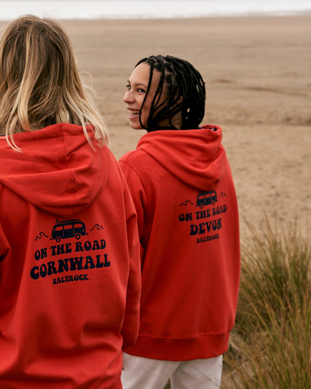 Two women wearing Saltrock hoodies standing on the beach.