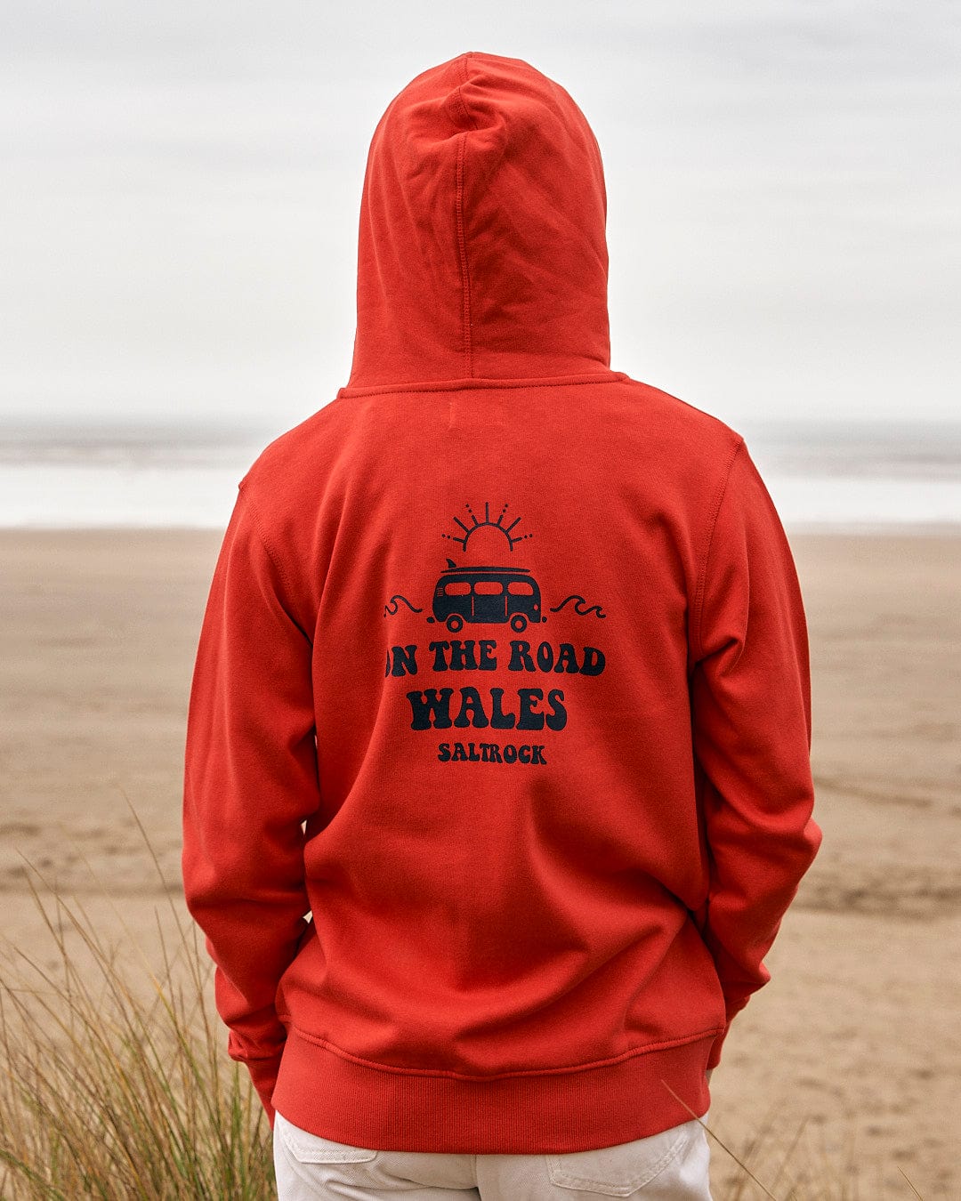 The back of a woman wearing a Saltrock On The Road Wales - Women's Zip Hoodie - Red.