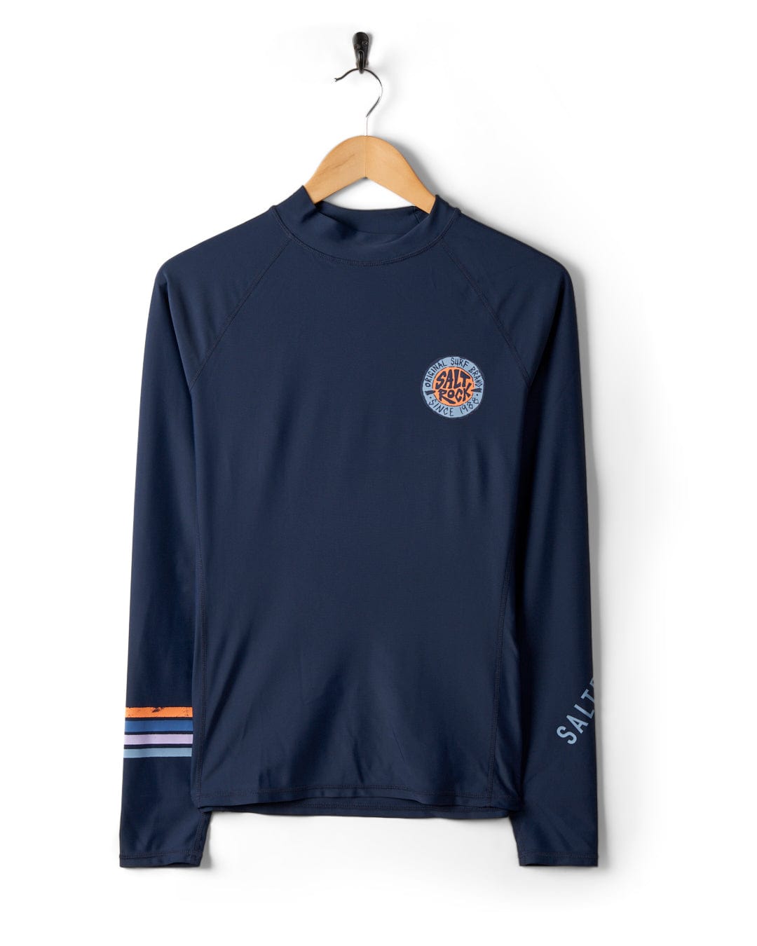Saltrock Navy Blue Long Sleeve Rashvest with UPF 50 protection, hanging on a hook against a white background, featuring a small logo on the chest and striped cuffs.