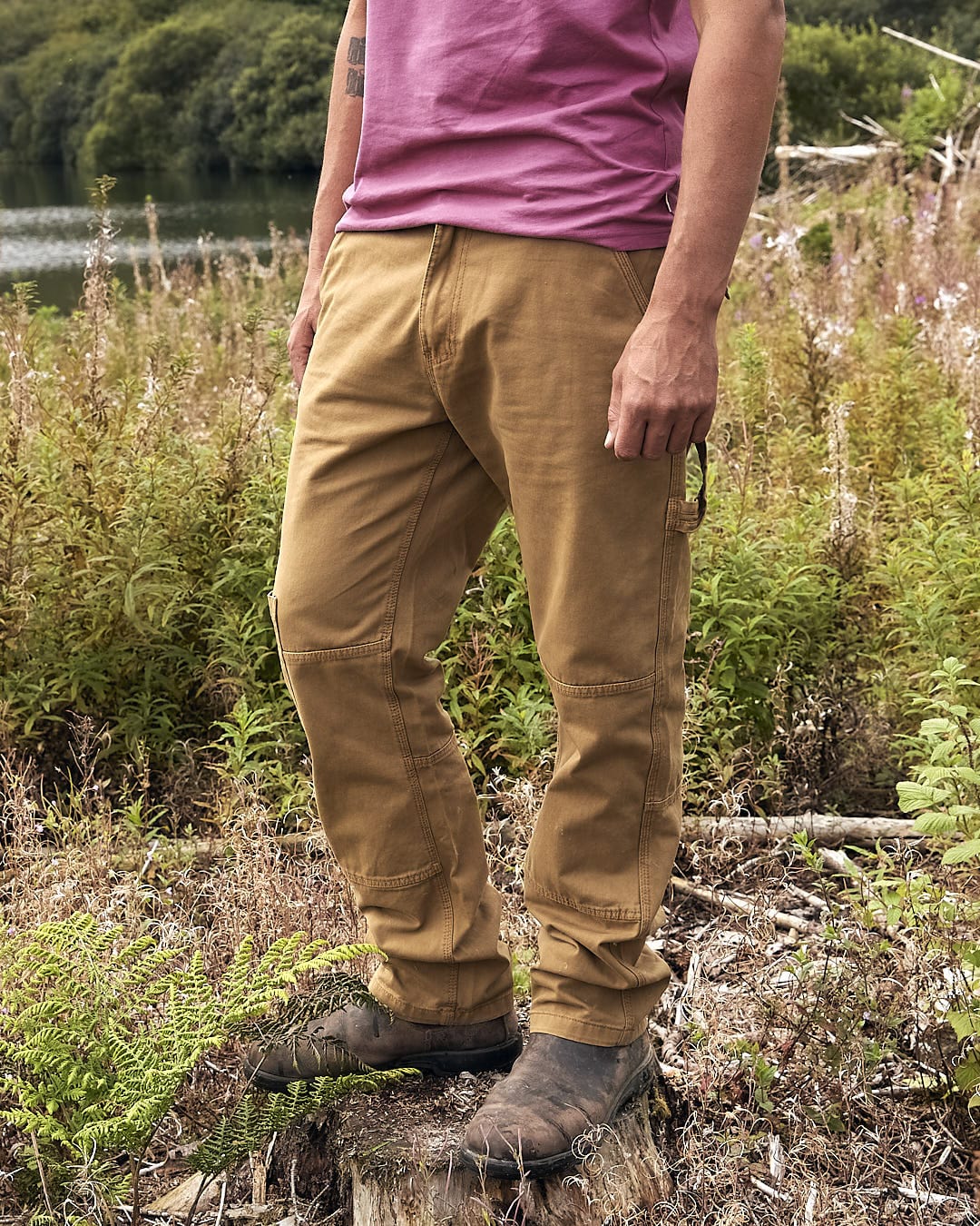 A man in Saltrock Oslo - Mens Carpenter Trouser - Brown standing next to a body of water.