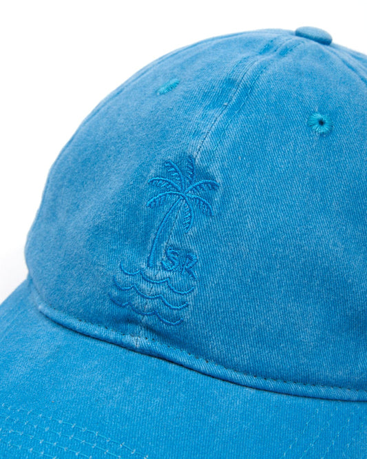 A close-up of a Cotton Blue Palm Cap with an embroidered palm tree design by Saltrock.
