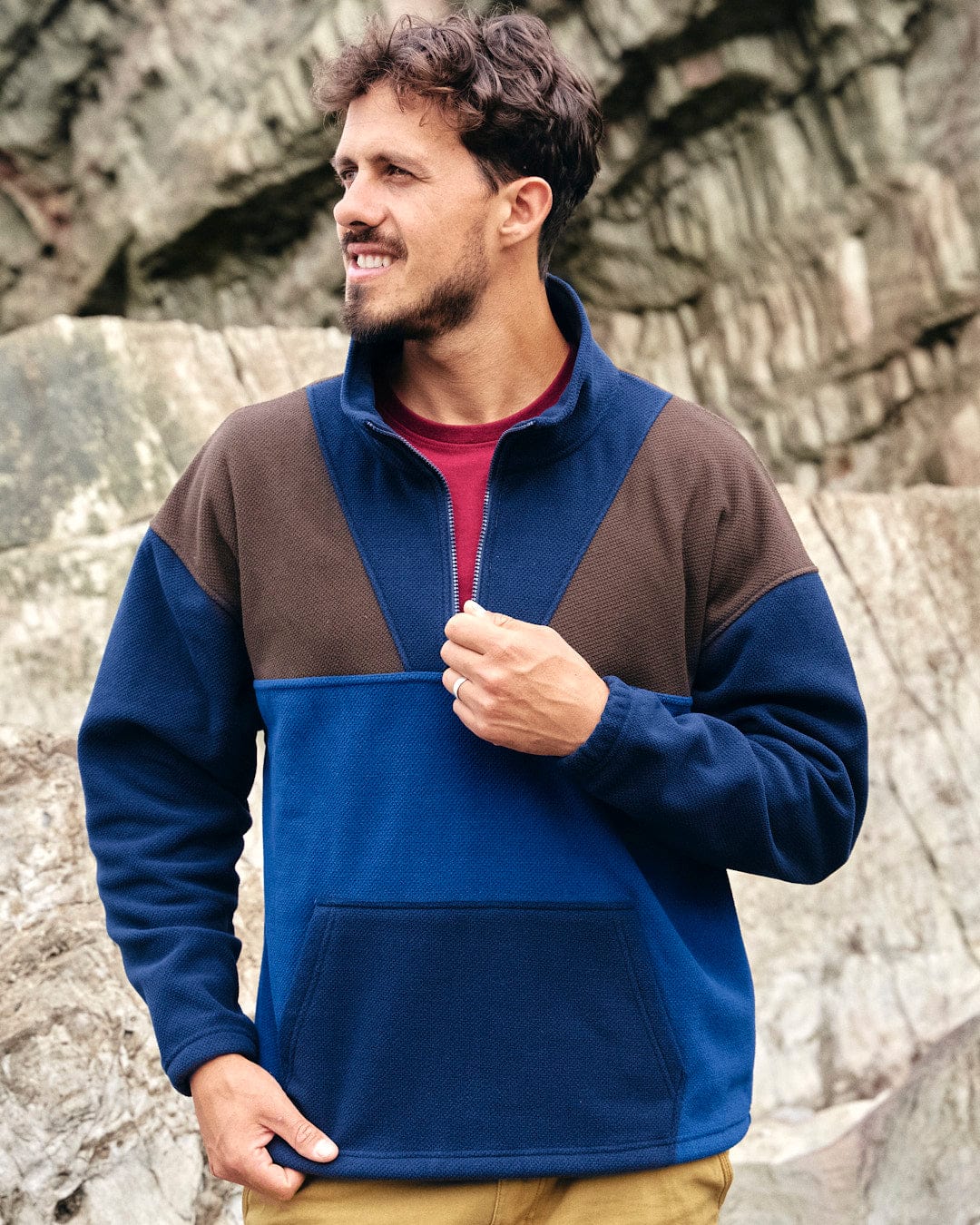 A stylish man wearing a Saltrock Peninsula - Mens 1/4 Zip Pullover Fleece in blue and brown, showcasing his activewear style.