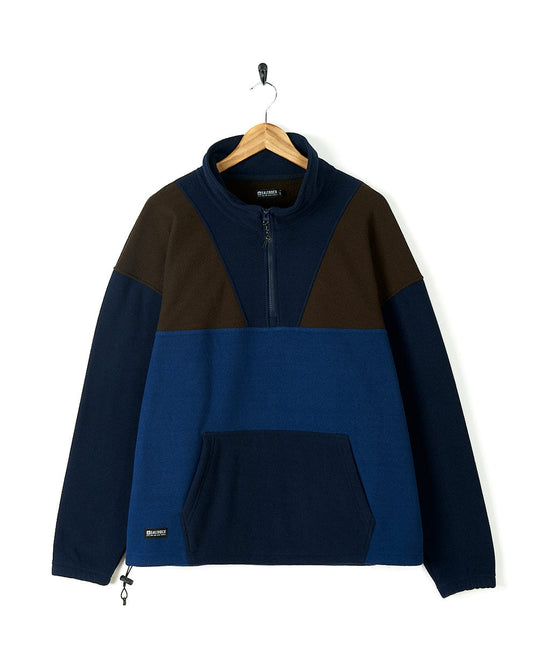 A Saltrock Peninsula Mens 1/4 Zip Pullover Fleece - Blue sweatshirt in a blue and brown color block style hanging on a hanger.