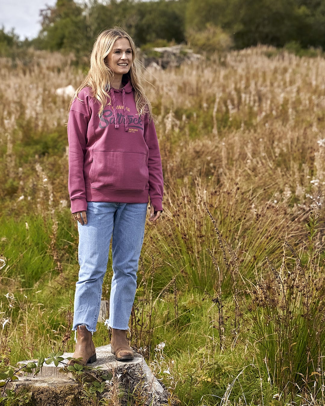 A woman standing in a field wearing a Saltrock Pennie - Ladies Pop Hoodie - Dark Pink.