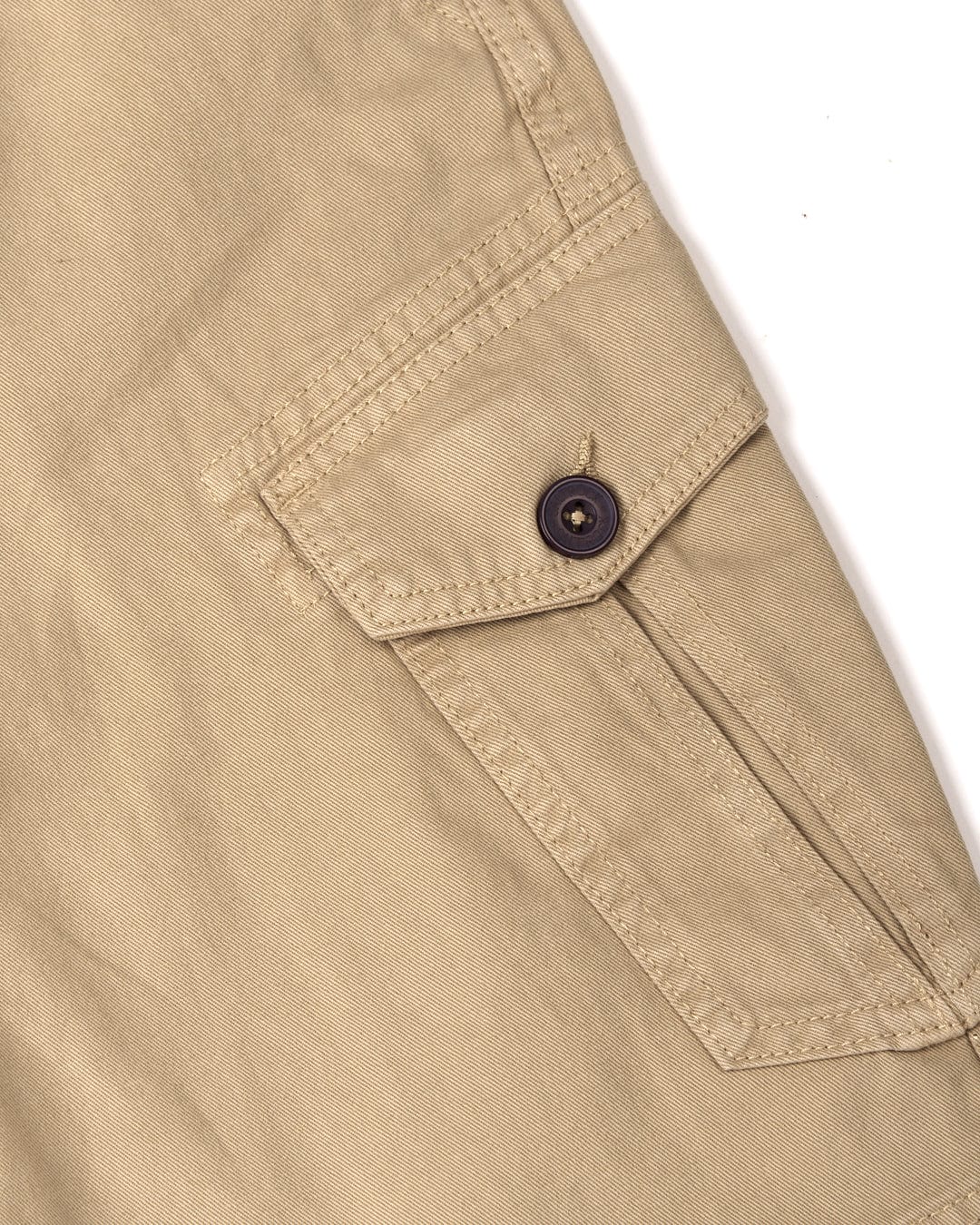 Close-up of a cotton material, khaki garment with a buttoned strap detail of Penwith II Mens Cargo Shorts in Cream by Saltrock.