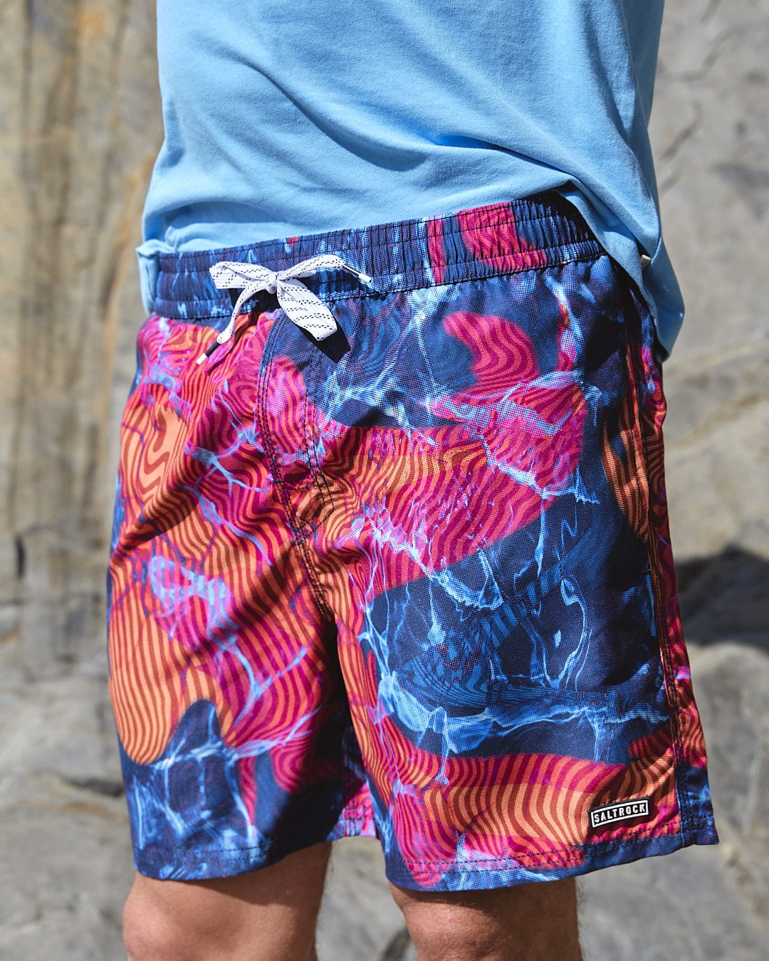 A man wearing a Saltrock Poolside - Mens All Over Print Swimshort in Teal shirt and blue shorts.