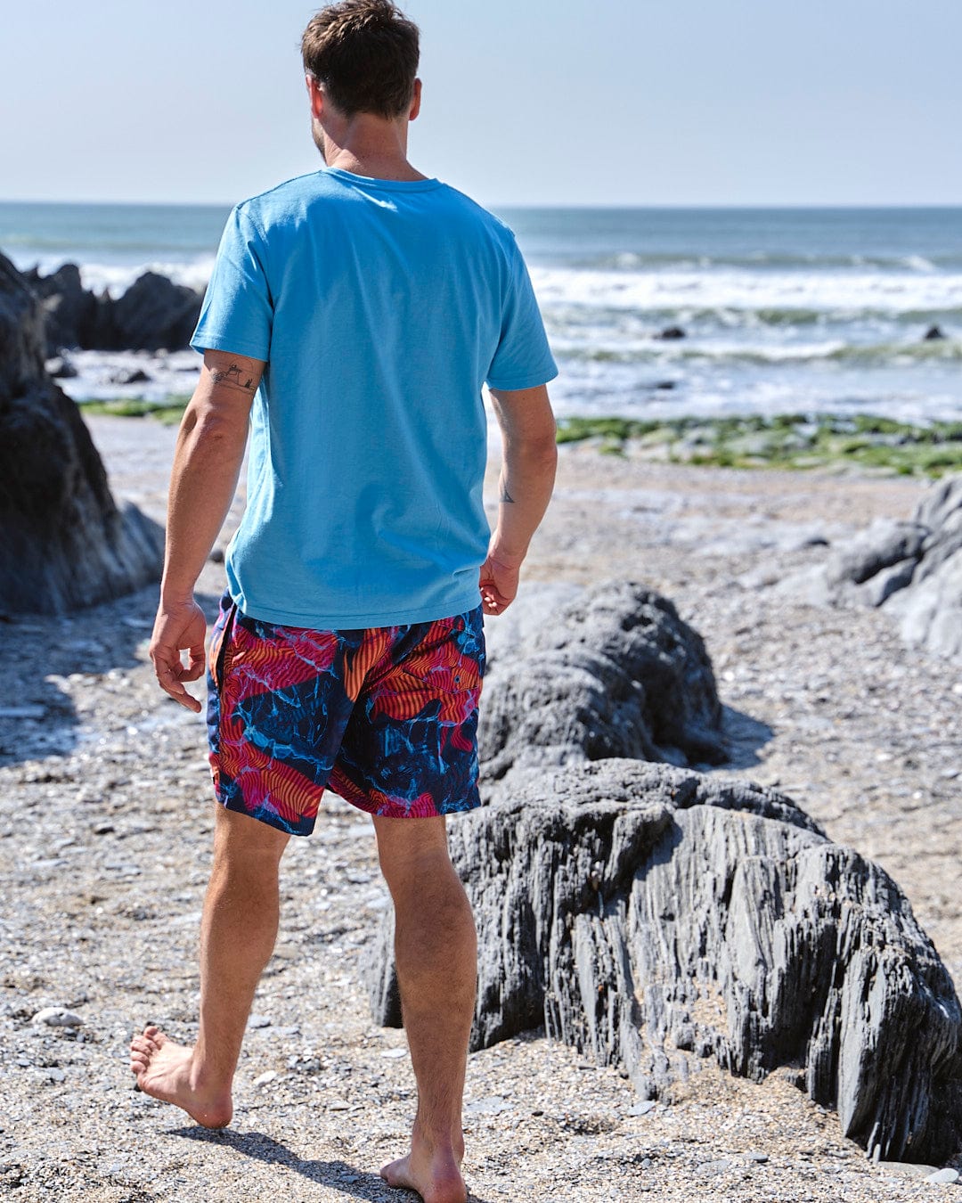 The man is wearing a Saltrock - Poolside Mens All Over Print Swimshort in Teal.