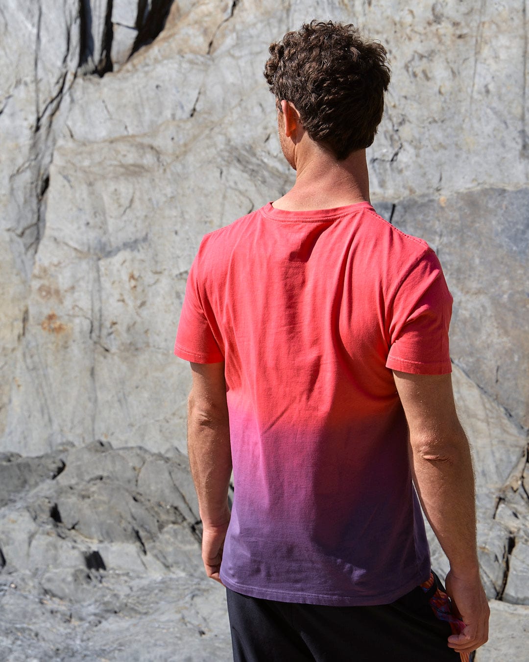 A man standing in front of a rock wearing Saltrock's Poolside - Mens Dip Die Short Sleeve T-Shirt in Pink.
