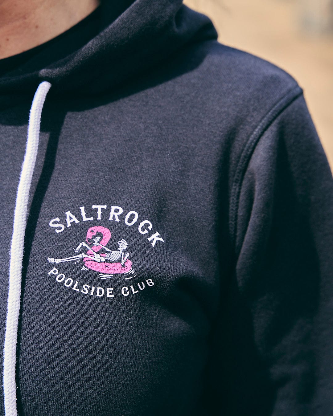 A woman wearing a Lee-Ann - Womens Zip Hoodie - Black by Saltrock that says "Saltrock poolside club.