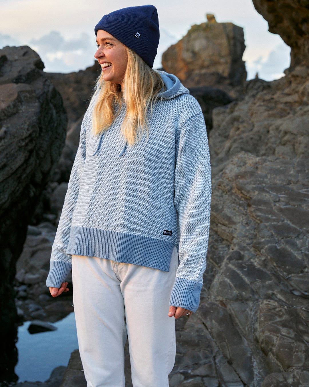 A woman smiling in front of the Poppy - Womens Knitted Pop Hoodie - Blue by Saltrock.