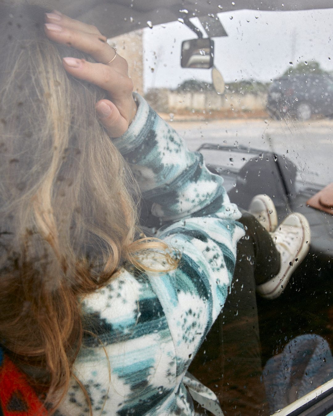 A woman sitting in a car on a rainy day, wrapped in a comfortable Saltrock Portis Womens Fleece in Green.