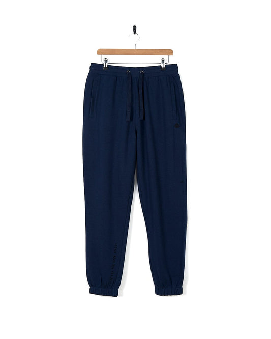 A Saltrock Premium Helston - Mens Jogger - Dark Blue, cuffed at the ankles, hangs on a hanger.