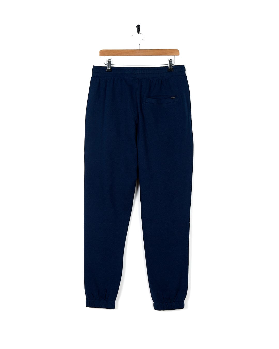 A pair of navy Saltrock Premium Helston Jogger sweatpants, cuffed at the ankles, hanging on a hanger with an elasticated waistband.
