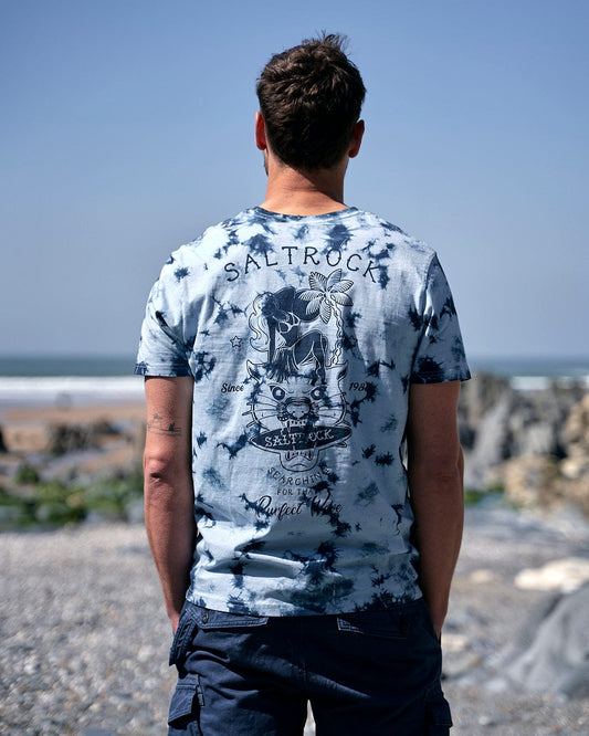 A man wearing a Saltrock Purfect Wave - Mens Tie Dye Short Sleeve T-shirt - Light Blue looking at the ocean.