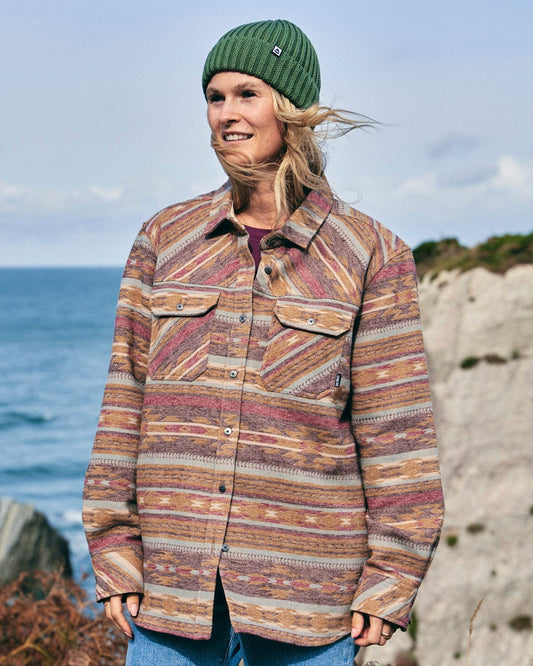 A woman wearing a Saltrock Quinn - Womens Heavy Overshirt in Brown and a beanie with buttoned cuffs.