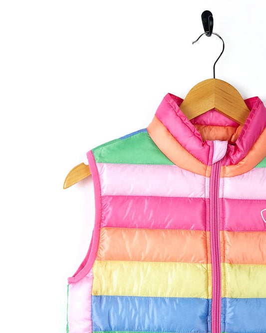 A lightweight Rainbow Bright - Kids Gilet - Multi/Pink by Saltrock hanging on a hanger.